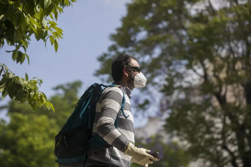 Un hombre camina con guantes y mascarilla.