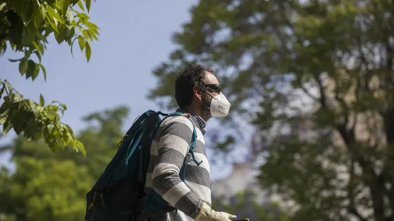 Un hombre camina con guantes y mascarilla.