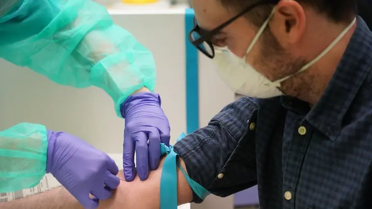 Un sanitario saca sangre a una persona.